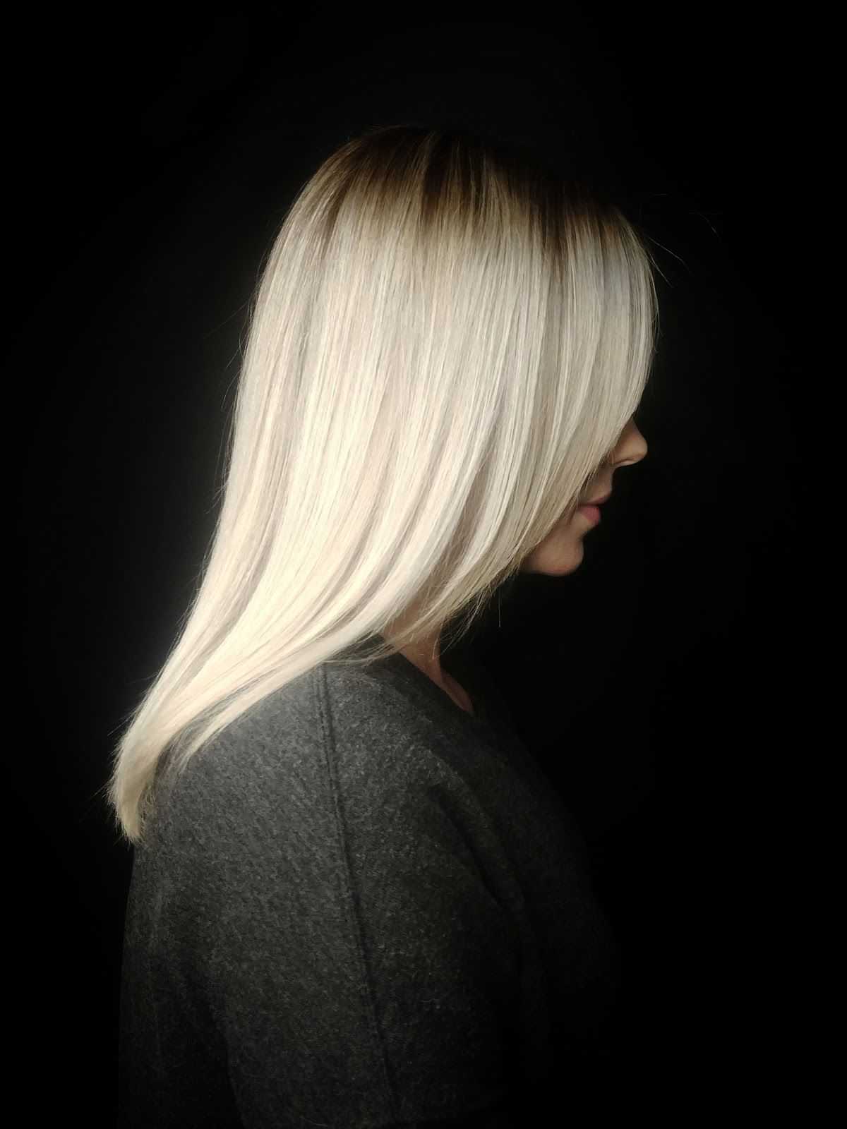 Profile of a woman with straight, long blonde hair against a dark background.